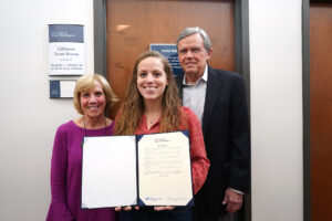 Michelle Gibbons '16, with her parents, Bill and Susie Gibbons, holds the BOV resolution naming the Gibbons Team Room, a collaboration and study space that will be used for business students for years to come. Photo by Suzanne Carr Rossi.