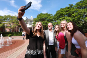 Class of 2024 grads pose for a selfie with President Troy Paino outside the Jepson Alumni Executive Center during the Senior Toast. Photo by Karen Pearlman.