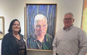 Kathleen and husband Terry pose with the portrait named after him, which was displayed in the UMW Galleries as part of the Mid-Atlantic New Painting Biennial, which ran Nov. 7 through Jan. 19. Photo courtesy of Kathleen Trenchard.