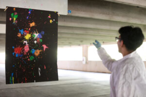 Alexander Rosas, a senior at Stafford High School, shows off his strategy of using heavily painted cotton balls on the right side of the canvas and reused cotton balls on the left side to demonstrate that the amount of energy put into an object correlates to its outcome. Alexander, who is involved with robotics and technology clubs in high school, said he was excited to connect with members of the physics community in Fredericksburg by participating in the PING program. Photo by K Pearlman Photography.