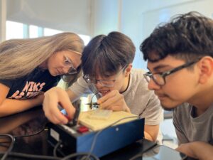 Hannah Steele '26, a UMW student mentor and Noyce Scholarship recipient, guides high schoolers Vincent Phan (left) and Alexander Rosas in creating a circuit. Photo by Katie Van Houten '27.