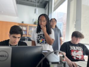 High schoolers Zubair Mohammadzai (left) and Tristan Towle (right) are guided in a lesson by volunteer mentor Emma Wallach, a Stafford High School sophomore who already participated in the PING program at Michigan State University, and UMW mentor Aliya Ather '28 (background). Photo by Katie Van Houten '27.