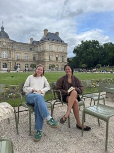 Description: Two college students sitting on benches in Luxembourg Gardens on an overcast day. Caption: Carly with a friend from the MICEFA program in Luxembourg Gardens in Paris. Photo courtesy of Carly Radgowski.