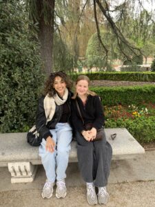 Description: Two college students on a bench in El Retiro Park in Madrid. Caption: Carly (right) with Hannah Anacko '26 in El Retiro Park in Madrid. Both students, who are co-presidents of UMW's French Language and Culture Club, studied abroad in France during their time at Mary Washington. Photo courtesy of Carly Radgowski.