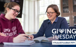 College student wearing a UMW psychology shirt sits at a table with Professor of Psychological Science Laura Wilson.