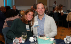 Two alumni pose for a photo at a formal event dinner.