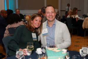 Two alumni pose for a photo at a formal event dinner.