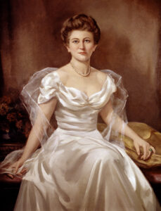 A portrait of Lettie Pate Whitehead wearing white satin dress and pearls, painted at the turn of the 20th century.