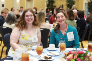 A smiling student and donor seated at a table.
