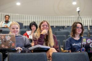 Several students in the Weatherly Wing, listening to a lecture and smiling.