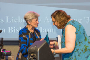 An alumna receives an award from another alumna.