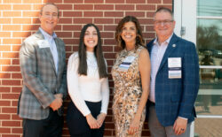A student and three donors standing against a brick wall.