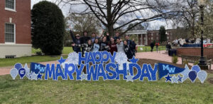 UMW students with the Happy Mary Wash Day sign outside the Cedric Rucker University Center.