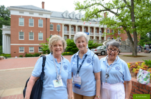 Three 1966 alumnae wearing matching shirts in front of Lee Hall.