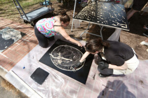 Two students ink a woodblock.