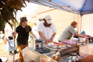 Three students experiment with screen-printing.