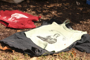 Red, white, and black shirts printed with 'Mary Washington is Mother' dry in the sun.