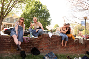 Students sitting on a brick wall and smiling.