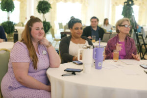 Three alumni sitting at a table and smiling.