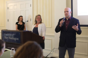 Two speakers present while an advancement staff member watches.