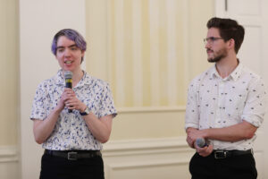 Two students holding mics present their project.
