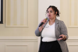 An alum and staff member speaks through a microphone.