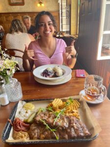 A smiling student with an excited hand gesture about to eat fruit dumplings at a table in a restaurant in the Czech Republic.