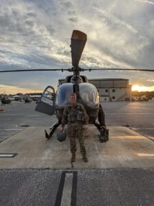 A photo of a UMW student who is a U.S. Army veteran in fatigues in front of a helicopter when he was still on active duty. 