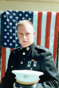 Sallie and George's son, George Keener Gill Jr., in his military uniform, standing in front of an American flag.