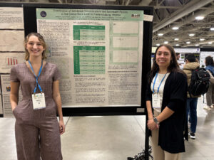 Two students standing in front of a poster.