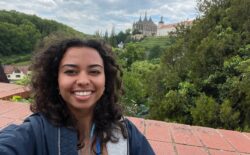 A student smiling with a village in Prague in the background.