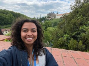 A student smiling with a village in Prague in the background.