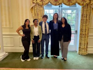 Five smiling students at the Jepson Alumni Executive Center ballroom.