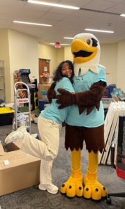 A student and UMW mascot Sammy D. Eagle wearing matching light blue T-shirts.