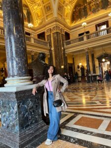 A student poses for a photo in an ornate museum in Prague.