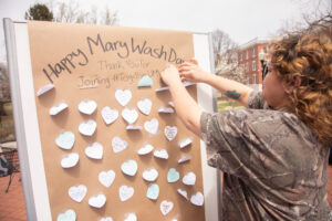 Students stick messages on a board that says Happy Mary Wash Day.