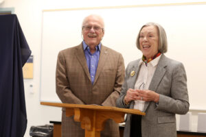 A couple smiling and talking at a podium.