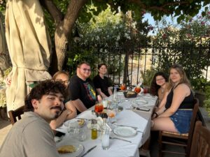 UMW students around a table outside, enjoying a meal in Greece.