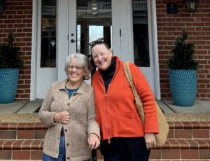 Two 1976 graduates standing on the steps of the Kalnen Inn at the University of Mary Washington.