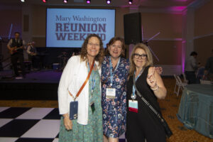 Three 1990s alumnae dressed up at the all-class party on a black-and-white checkered floor.