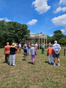 A group of people with their backs to the camera facing Thomas Jefferson's Poplar Forest on a sunny day.