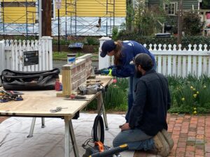 Two people working on historic mortar at a table set up outside the Mary Washington House.